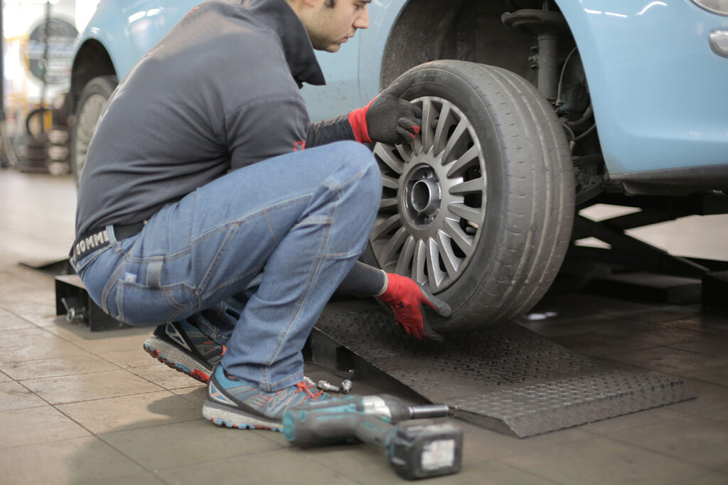 technician performing a brake replacement of bad brake pads with new brake pads